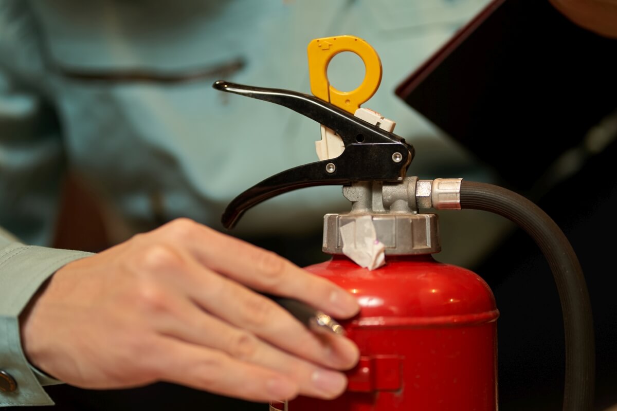 Ręka trzymająca gaśnicę podczas serwisu gaśnic.